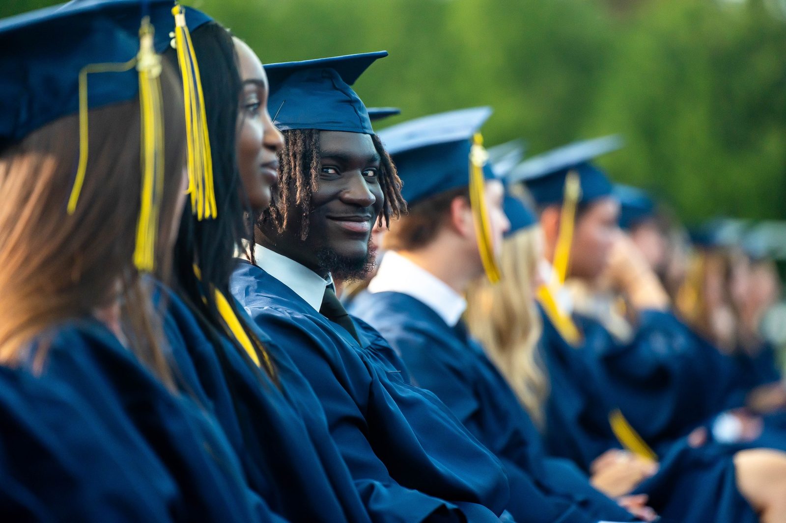 Graduates in navy caps and gowns with gold tassels at a Lasallian Catholic high school commencement